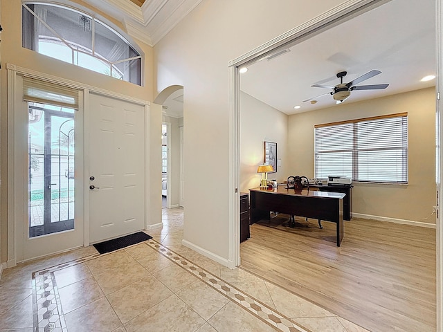 entryway featuring visible vents, baseboards, arched walkways, ornamental molding, and light tile patterned flooring