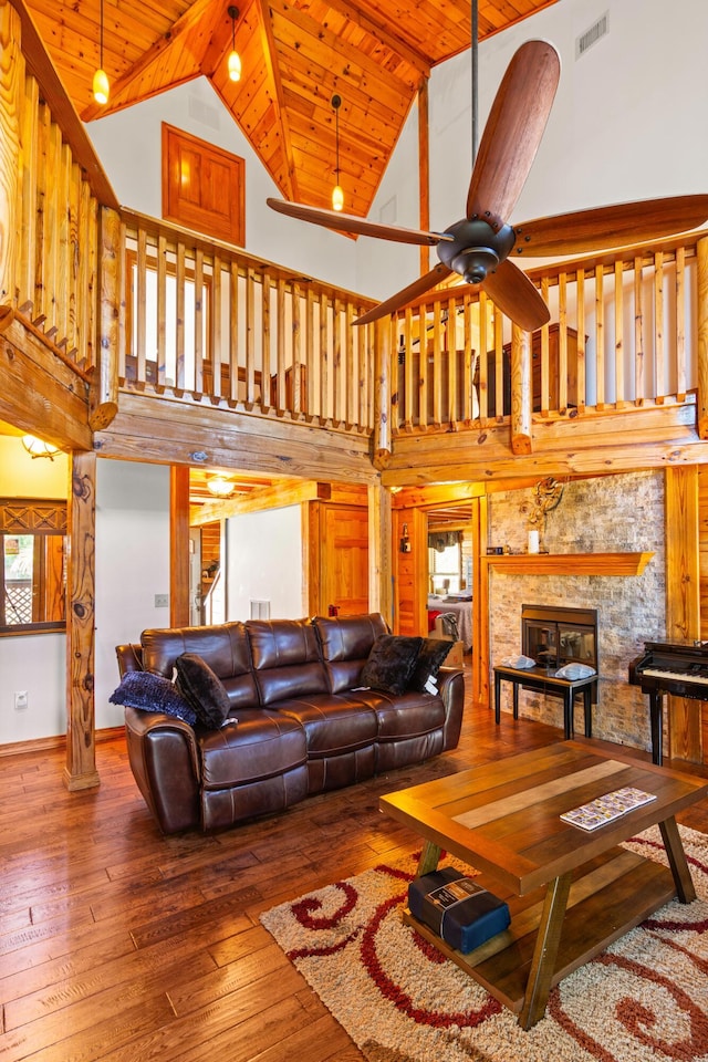 living room with high vaulted ceiling, wood ceiling, visible vents, hardwood / wood-style floors, and a glass covered fireplace