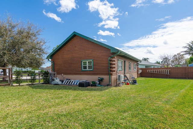 view of property exterior with a fenced backyard, a yard, central AC unit, and log siding