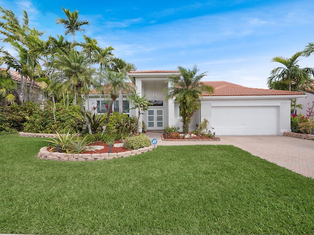 mediterranean / spanish-style house with french doors, decorative driveway, a front yard, and an attached garage