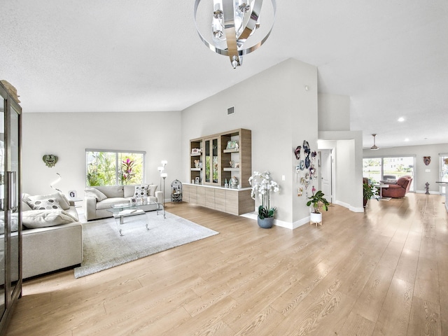 living area with visible vents, light wood-style flooring, baseboards, and vaulted ceiling