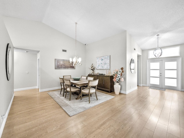 dining room featuring light wood finished floors, visible vents, baseboards, french doors, and a notable chandelier