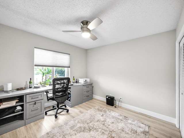 office space featuring light wood-style flooring, a textured ceiling, baseboards, and a ceiling fan