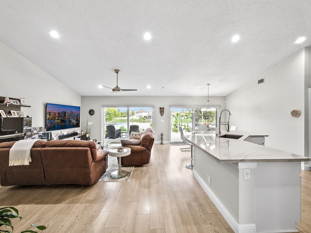 living room featuring recessed lighting, visible vents, light wood-style flooring, and a textured ceiling