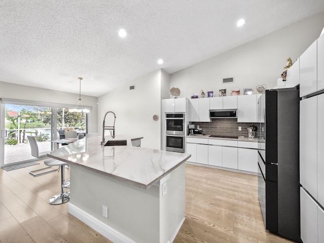 kitchen with visible vents, a sink, extractor fan, appliances with stainless steel finishes, and backsplash