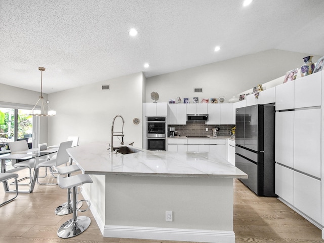 kitchen with a spacious island, visible vents, vaulted ceiling, appliances with stainless steel finishes, and a sink