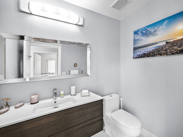 half bath featuring visible vents, toilet, and vanity