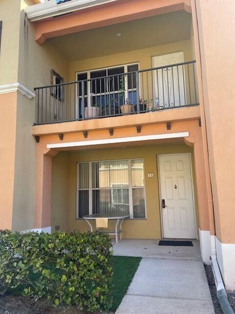 entrance to property featuring a balcony and stucco siding