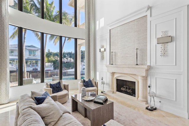 living area featuring a high ceiling, a high end fireplace, and a decorative wall