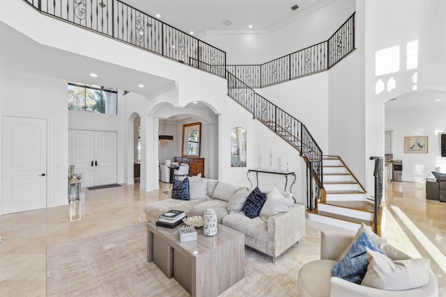 living area with stairway, ornamental molding, a high ceiling, arched walkways, and marble finish floor