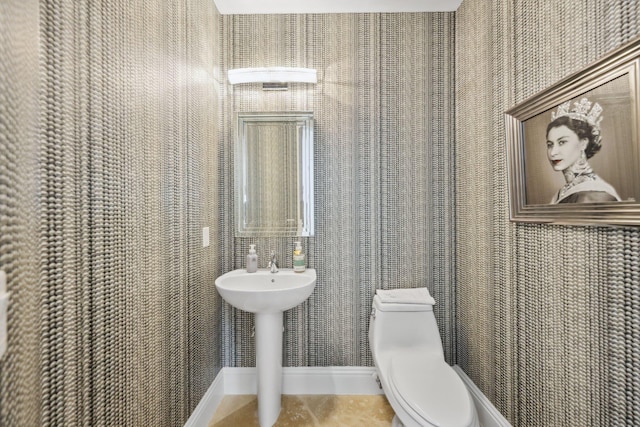 half bathroom featuring baseboards, toilet, and tile patterned flooring