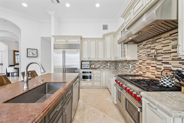 kitchen with high end appliances, visible vents, arched walkways, a sink, and under cabinet range hood