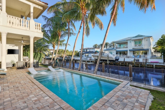 view of pool with a water view, a patio, a dock, a fenced in pool, and ceiling fan