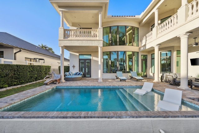 back of property featuring a patio area, an outdoor living space, a balcony, and a fenced in pool