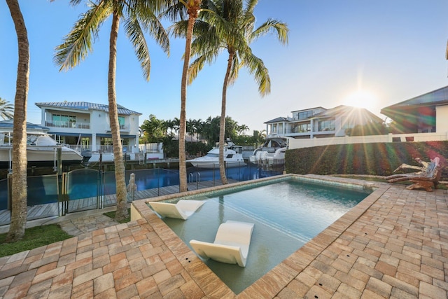 outdoor pool with a water view, a patio, and a dock