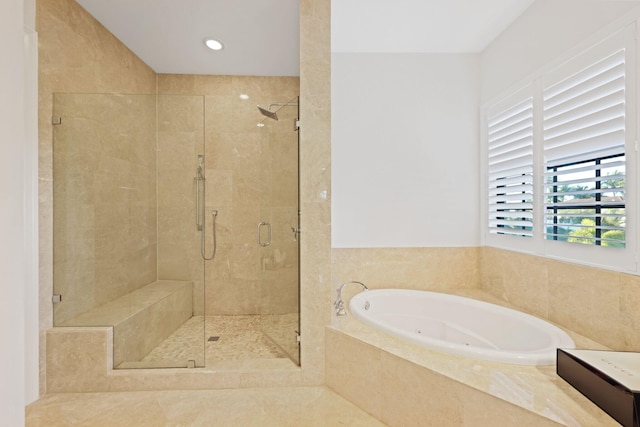 bathroom with recessed lighting, a tub with jets, and a stall shower