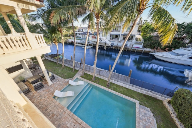 view of pool featuring a fenced in pool, a water view, fence, a boat dock, and a patio