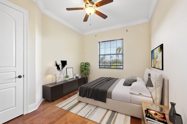 bedroom with ceiling fan, baseboards, wood finished floors, and crown molding