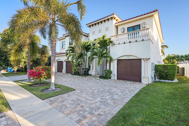 mediterranean / spanish home featuring a balcony, decorative driveway, a garage, and stucco siding