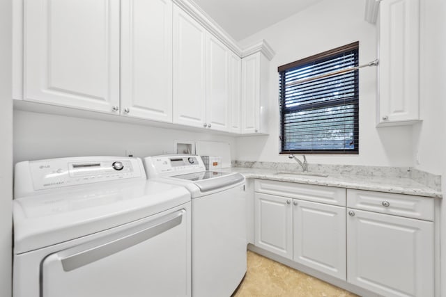 clothes washing area featuring cabinet space, washer and dryer, and a sink