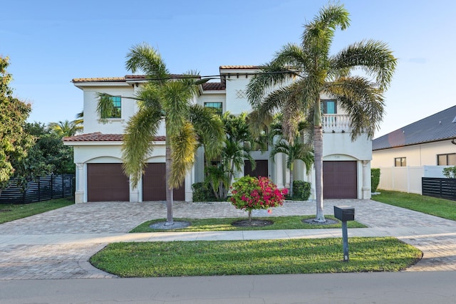 mediterranean / spanish-style home featuring fence, a tile roof, stucco siding, decorative driveway, and a garage