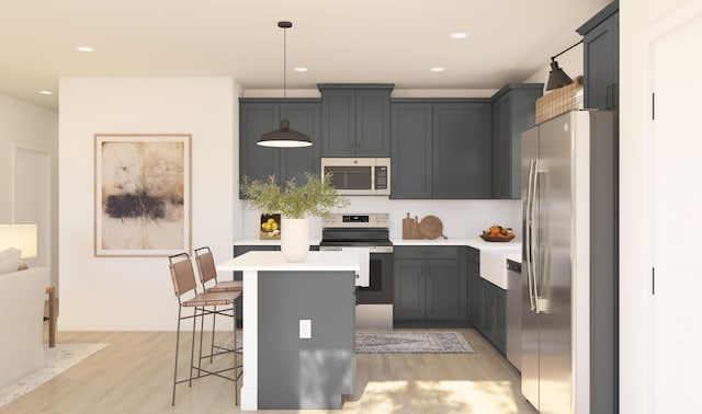 kitchen with a center island, stainless steel appliances, light wood-style floors, a breakfast bar area, and light countertops