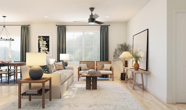 living room featuring recessed lighting, ceiling fan with notable chandelier, baseboards, and light wood-style floors