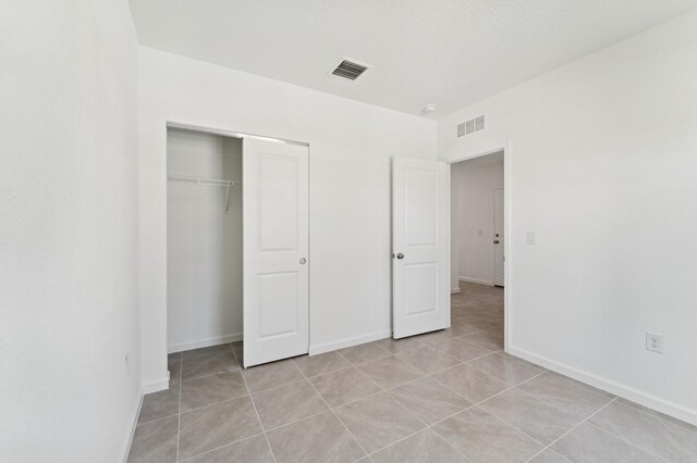 322 Becker Rd Unit 13, Port Saint Lucie, FL 34953 - unfurnished bedroom featuring light tile patterned flooring, a closet, and baseboards