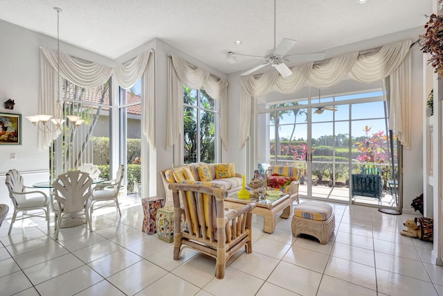 living room featuring ceiling fan with notable chandelier, a textured ceiling, and light tile patterned floors