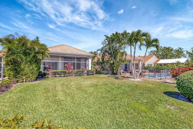 view of yard featuring a sunroom, fence, and a fenced in pool