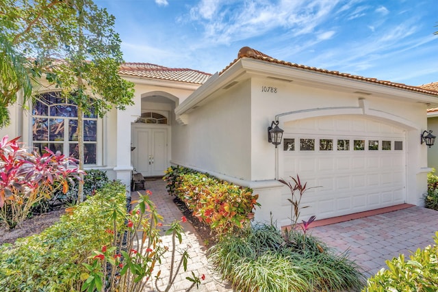 view of front of home with a garage, decorative driveway, a tile roof, and stucco siding