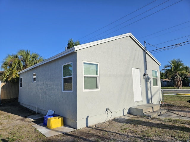 rear view of property featuring stucco siding and fence