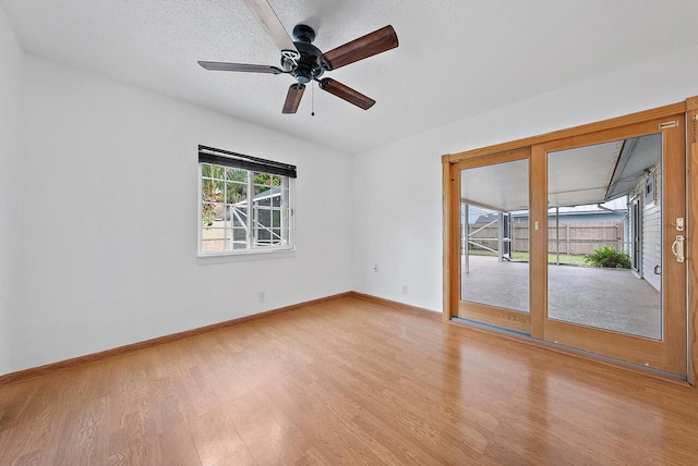 unfurnished room featuring a ceiling fan, light wood-style flooring, baseboards, and a textured ceiling