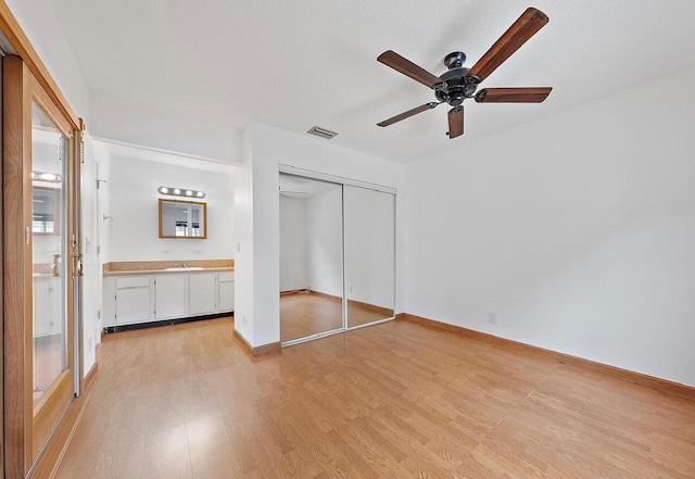 unfurnished bedroom with ceiling fan, visible vents, a closet, light wood-type flooring, and ensuite bath