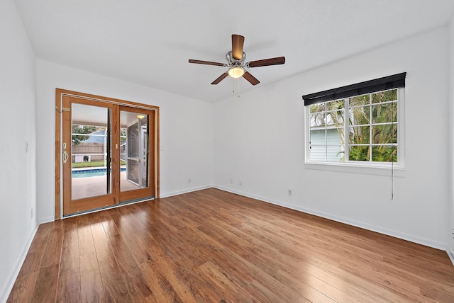 empty room featuring a ceiling fan, baseboards, and hardwood / wood-style flooring