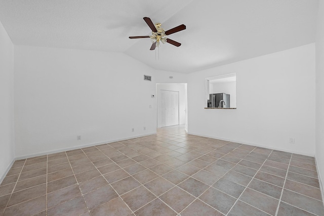 empty room with lofted ceiling, visible vents, baseboards, a ceiling fan, and tile patterned floors