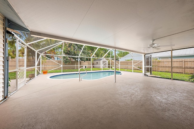 view of swimming pool featuring a patio area, a fenced backyard, glass enclosure, and a storage unit