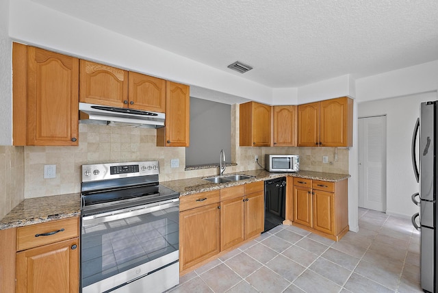 kitchen featuring under cabinet range hood, a sink, visible vents, appliances with stainless steel finishes, and light stone countertops