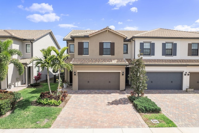 view of front facade with decorative driveway, an attached garage, and stucco siding