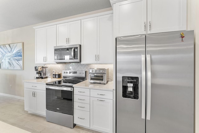 kitchen featuring tasteful backsplash, baseboards, light countertops, appliances with stainless steel finishes, and white cabinetry