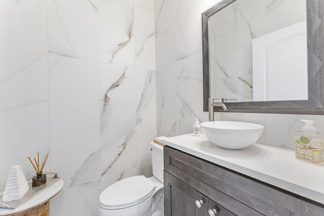 half bathroom featuring toilet, tile walls, and vanity