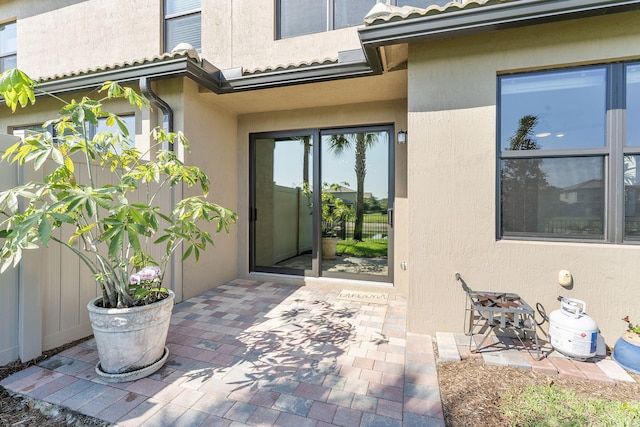 entrance to property featuring stucco siding, a patio, and a tiled roof