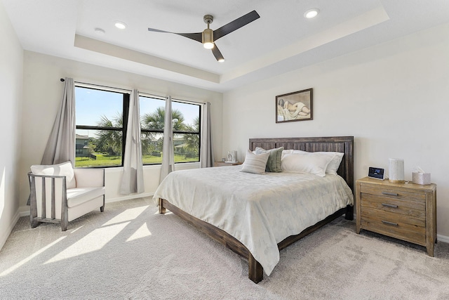 bedroom with light carpet, baseboards, and a tray ceiling