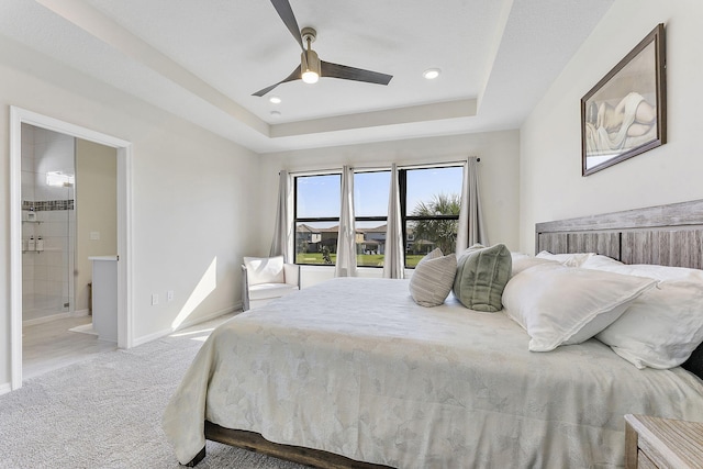 carpeted bedroom featuring ceiling fan, a raised ceiling, baseboards, and connected bathroom