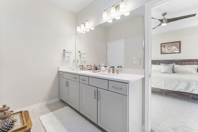 bathroom featuring a sink, connected bathroom, double vanity, baseboards, and ceiling fan