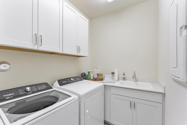 clothes washing area featuring cabinet space, washer and dryer, and a sink