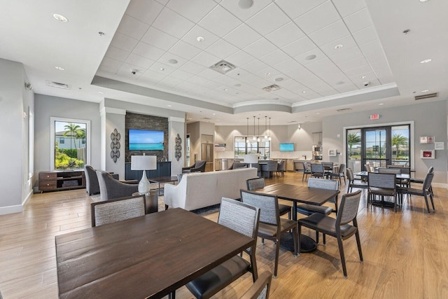 dining space featuring light wood-type flooring, a raised ceiling, and plenty of natural light