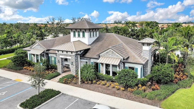 exterior space featuring a standing seam roof, uncovered parking, stucco siding, stone siding, and metal roof