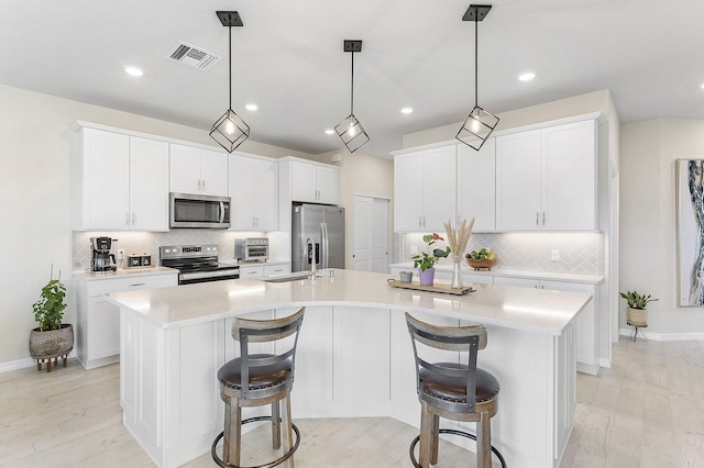 kitchen featuring visible vents, a large island, white cabinets, light countertops, and appliances with stainless steel finishes