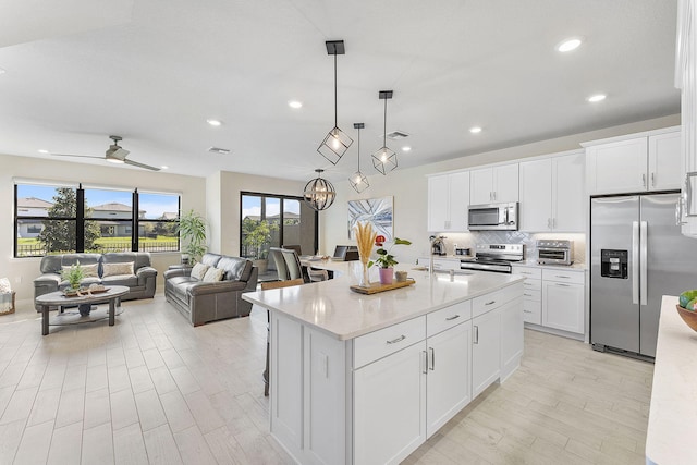 kitchen featuring a toaster, decorative backsplash, white cabinetry, and stainless steel appliances